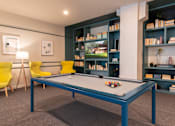 Thumbnail 33 of 43 - A pool table in a room with a yellow chair and a bookshelf.