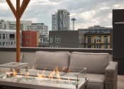 Thumbnail 23 of 34 - Luxury Apartments for Rent in Seattle, WA - Union Bay - Firepit Area with Raised Firepit, City View, and Patio Furniture