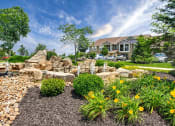 Thumbnail 48 of 48 - Riverstone - Landscaping with stone fountain, yellow flowers, trees, and shrubs