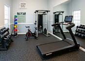 Thumbnail 3 of 14 - A gym with a treadmill, weights and exercise bikes.