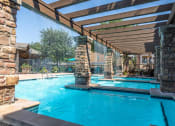 Thumbnail 24 of 48 - a resort style swimming pool with stone columns and a wooden canopy over it