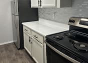 Thumbnail 2 of 19 - Open concept  kitchen with white cabinets and a stove and a refrigerator