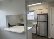 Thumbnail 1 of 19 - a kitchen with a white counter top and a stainless steel refrigerator
