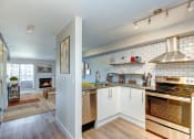 Thumbnail 2 of 34 - Seattle Luxury Apartments - Union Bay - Kitchen with White Tile Backsplash, Stainless-Steel Appliances, and Floating Shelves