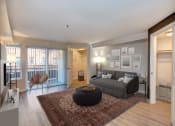 Thumbnail 7 of 34 - Seattle, WA Luxury Apartments - Union Bay- Living Room with Grey Couch, Patio Entrance, and Circle Coffee Table