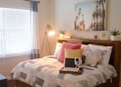 Thumbnail 6 of 65 - A bed with a quilt and a lamp on it.