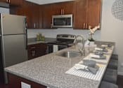 Thumbnail 7 of 65 - A kitchen with a granite countertop and stainless steel appliances.