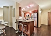 Thumbnail 27 of 28 - A kitchen with a refrigerator, microwave, and bar stools.