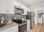 Thumbnail 1 of 31 - A kitchen with white cabinets and a black refrigerator.