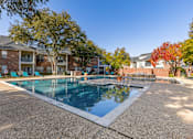 Thumbnail 21 of 24 - A large outdoor swimming pool surrounded by trees and apartment buildings.