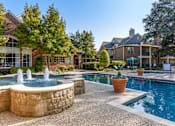 Thumbnail 19 of 24 - A pool with a fountain in the middle of a backyard.