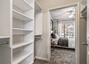 Thumbnail 5 of 24 - A white closet with shelves and a mirrored doorway leading to a bedroom.
