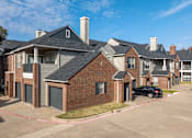 Thumbnail 23 of 24 - A black car is parked in front of a brick house.