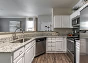 Thumbnail 1 of 24 - A modern kitchen with white cabinets and stainless steel appliances.
