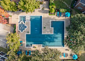 Thumbnail 17 of 24 - An aerial view of a swimming pool surrounded by trees and a small building.