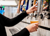 Thumbnail 28 of 38 - A person is pouring a beer from a tap into a cup.