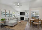 Thumbnail 1 of 22 - A living room with a grey couch, a fireplace, a television, and a dining table.