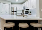 Thumbnail 2 of 22 - A kitchen with white cabinets and a white counter top.