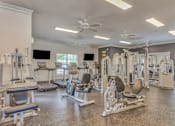 Thumbnail 9 of 20 - A spacious gym with a variety of equipment including treadmills, weight machines, and a bench press.
