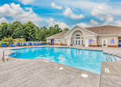 Thumbnail 3 of 20 - A large outdoor swimming pool with a building in the background.