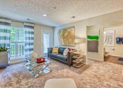 Thumbnail 4 of 20 - A living room with a couch, coffee table, and a painting on the wall.