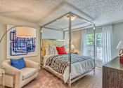 Thumbnail 6 of 20 - A bedroom with a four poster bed and a blue chair.