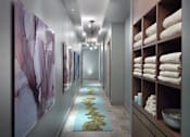Thumbnail 31 of 38 - A hallway with a row of towels on the right and artwork on the wall.