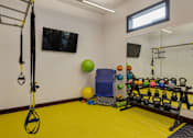 Thumbnail 33 of 47 - A gym room with a yellow floor and a variety of exercise equipment.