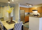 Thumbnail 16 of 25 - Ardenne Apartments kitchen and dining room with blue and white chairs, yellow flowers and stainless steel appliances