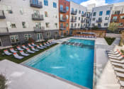 Thumbnail 4 of 37 - Sparkling resort style swimming pool with cushioned lounge chairs