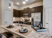 Thumbnail 22 of 37 - Granite counter tops, stainless appliance package, medium brown cabinets, plank wood-style flooring, island seating, abundant cabinet and pantry space