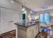 Thumbnail 25 of 37 - Granite counter tops, stainless appliance package, medium brown cabinets, plank wood-style flooring, island seating, abundant cabinet and pantry space