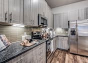 Thumbnail 27 of 37 - Granite counter tops, stainless appliance package, medium brown cabinets, plank wood-style flooring, island seating, abundant cabinet and pantry space