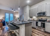 Thumbnail 26 of 37 - Granite counter tops, stainless appliance package, medium brown cabinets, plank wood-style flooring, island seating, abundant cabinet and pantry space
