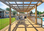 Thumbnail 23 of 26 - A wooden deck with a table and chairs overlooking a pool.