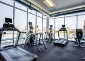 Thumbnail 14 of 31 - a gym with floor to ceiling windows and cardio equipment