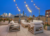 Thumbnail 1 of 31 - a rooftop terrace with chairs and tables and a city skyline in the background