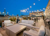 Thumbnail 4 of 31 - a rooftop terrace with couches and tables and a city at night