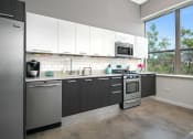 Thumbnail 25 of 31 - a kitchen with white cabinets and stainless steel appliances and a window