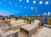 Thumbnail 3 of 31 - a rooftop terrace with couches and tables and a city skyline