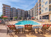 Thumbnail 2 of 19 - a swimming pool with patio furniture in front of an apartment building