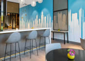 Thumbnail 11 of 31 - a dining room with a table and chairs and a blue wall with a skyline painted