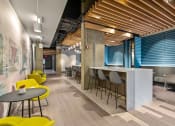 Thumbnail 16 of 31 - a communal area with yellow chairs and tables and a bar with blue and white walls