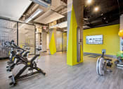 Thumbnail 14 of 31 - a gym with cardio equipment and weights in a building with yellow walls