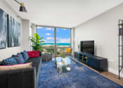 Thumbnail 2 of 31 - a living room with a couch and a tv and a view of the ocean