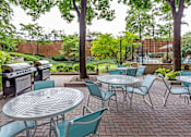 Thumbnail 10 of 34 - A patio with a table and chairs and a grill.