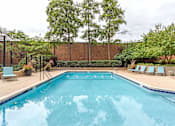 Thumbnail 9 of 34 - A large swimming pool surrounded by trees and lounge chairs.