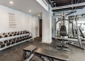 Thumbnail 12 of 34 - A gym with a bench, weights, and a wall-mounted sign.