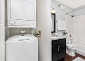 Thumbnail 33 of 34 - A white washing machine and dryer are installed in a small bathroom.