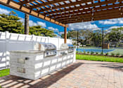 Thumbnail 14 of 22 - A white outdoor kitchen with a grill and a pergola.